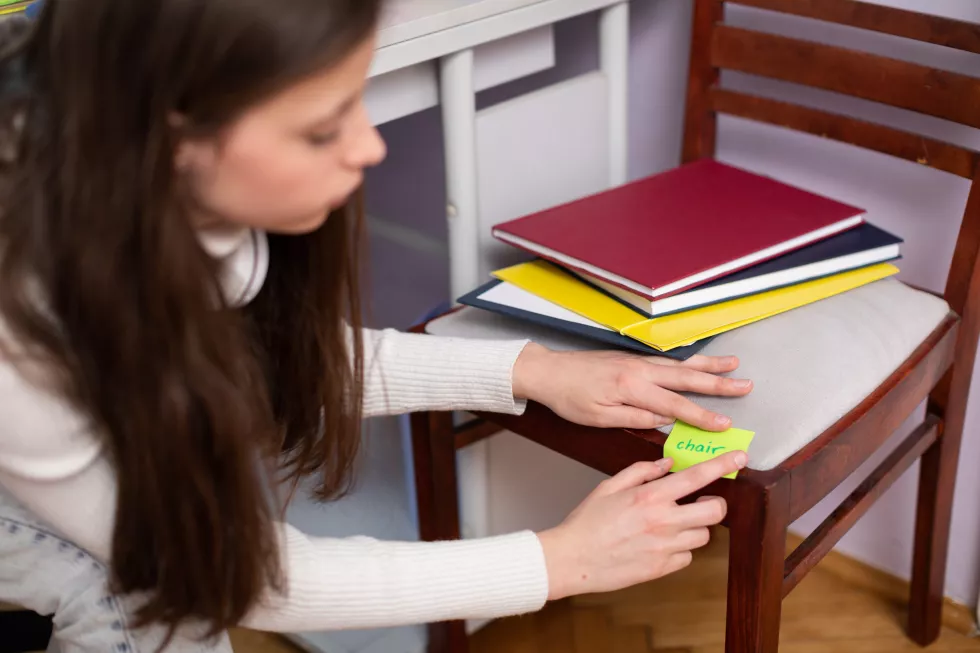 girl-sticks-card-chair-while-learning-english