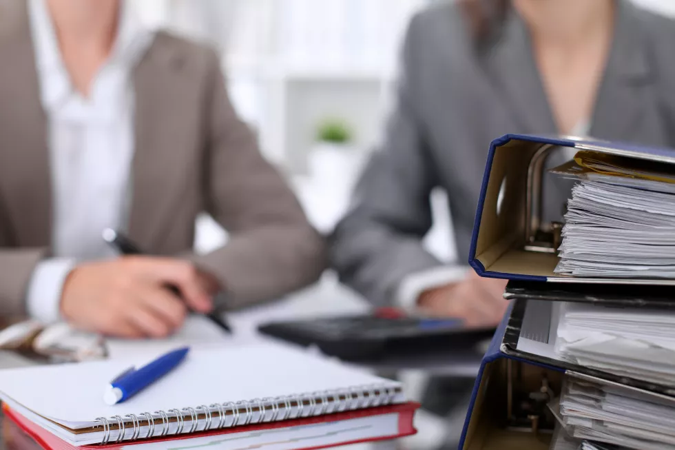 binders-with-papers-are-waiting-be-processed-with-businessman-secretary-back-blur-internal-revenue-service-inspector-checking-financial-document