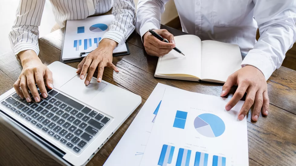 midsection-businessman-colleague-working-graph-while-using-laptop-table