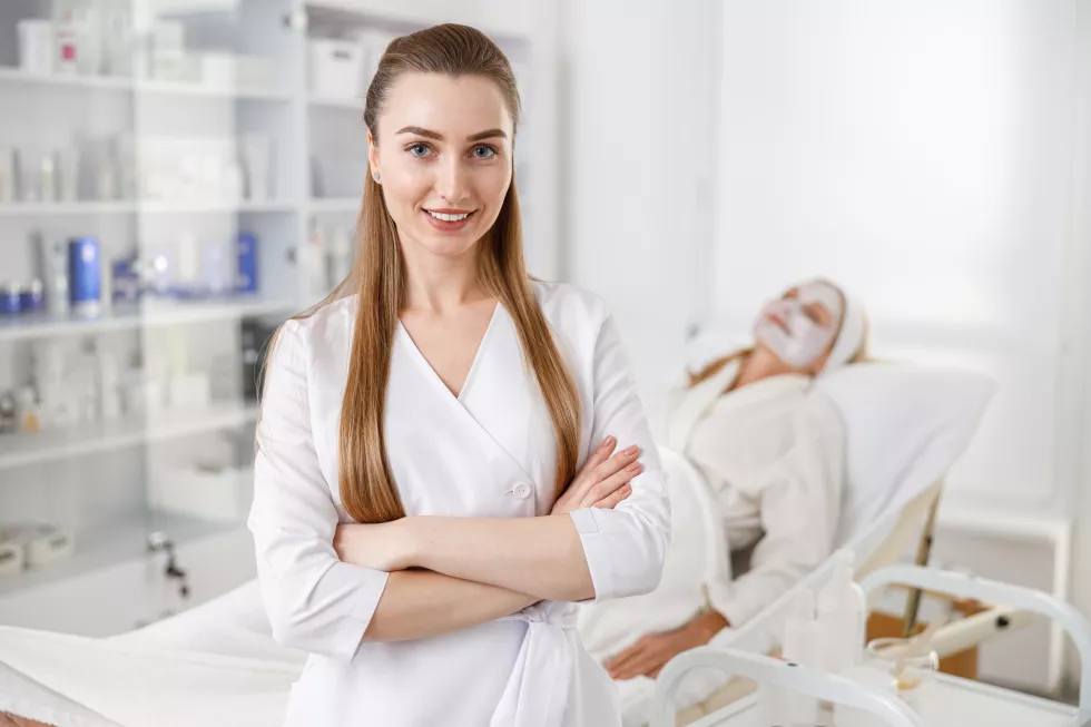 dermatologist-with-hands-crossed-standing-by-patient-lying-couch-while-medical-procedure