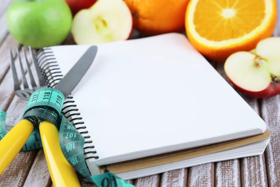 cutlery-tied-with-measuring-tape-notebook-with-fruits-wooden-background (1)