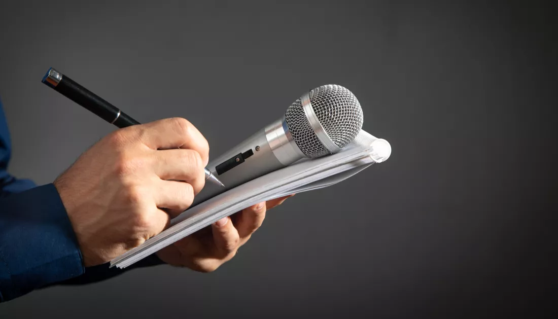 caucasian-journalist-holding-microphone-notepad-pen