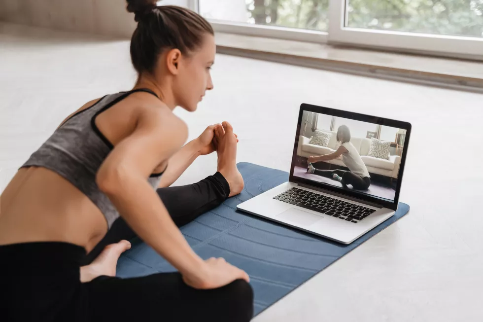 fit-woman-sportswear-doing-yoga-exercise-mat-home-using-laptop-watching-tutorial-female-coach-has-virtual-yoga-class-computer