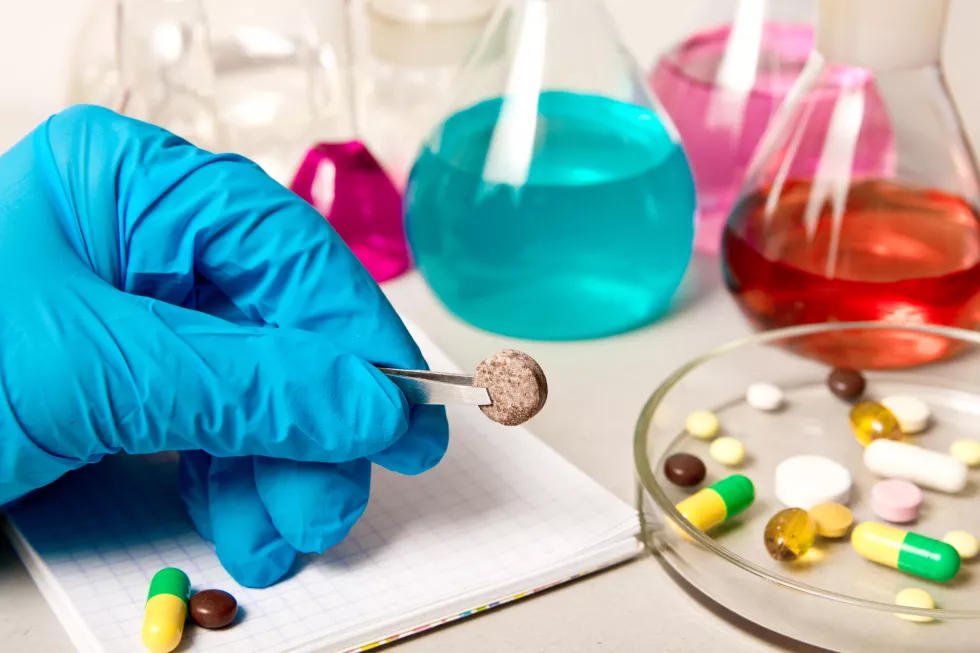 holds-pills-against-background-chemical-laboratory-reagents
