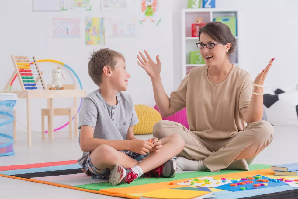 teacher-boy-sit-floor-with-colorful-puzzle