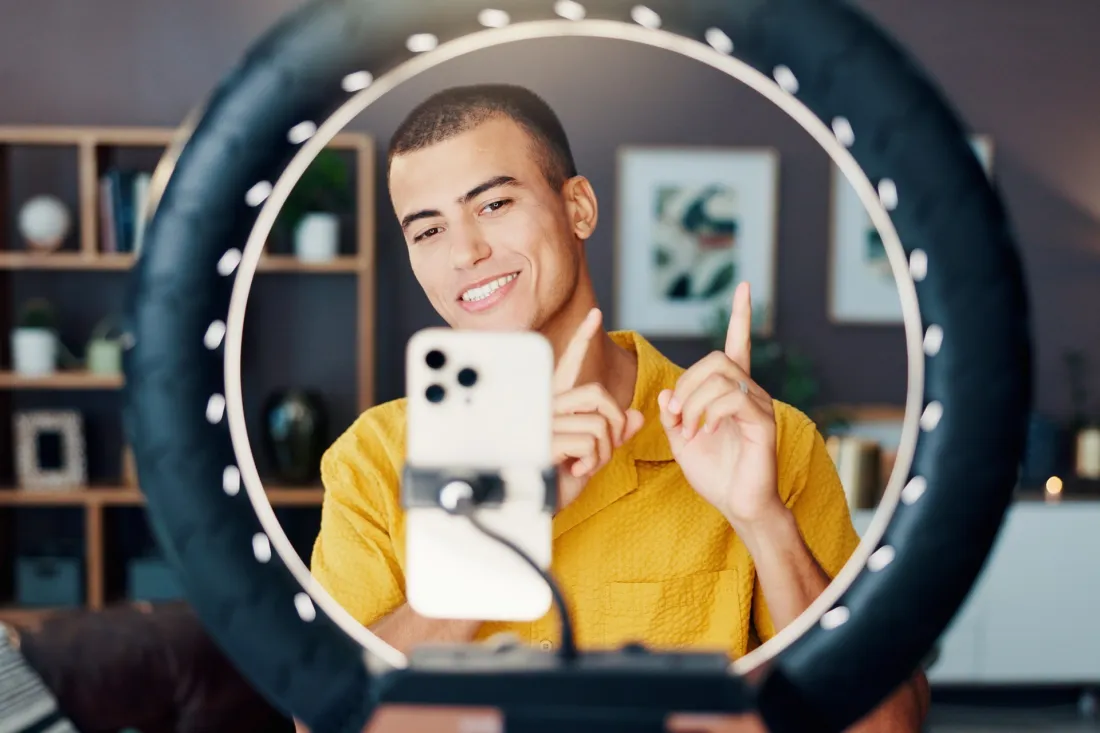 A young content creator records a video with a smartphone and a ring light